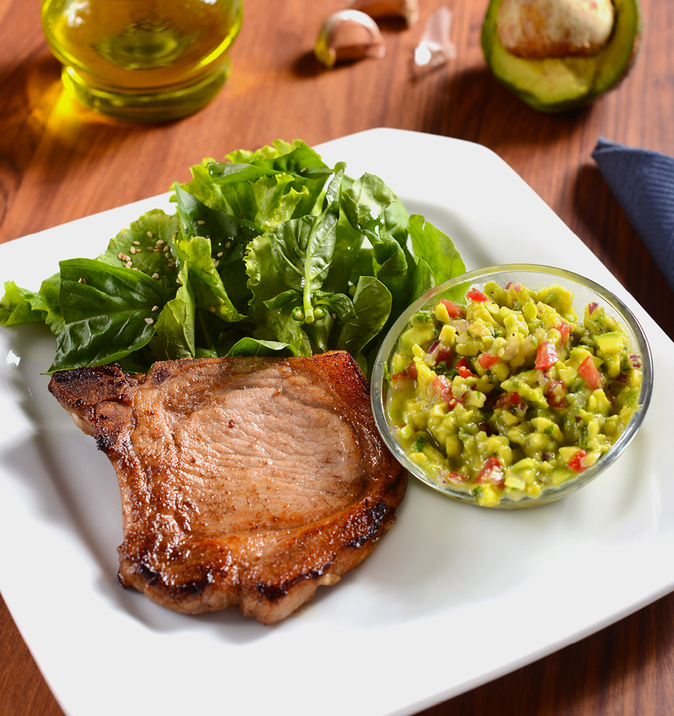 Costeletas de cerdo con mix de hojas verdes y guacamole